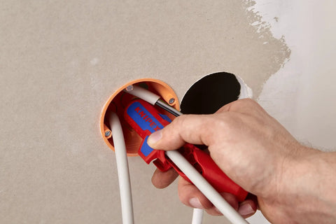 Using Workhorse Ergostrip Cable Stripping Tool With Ergonomic Pistol Grip on cables through a drywall hole