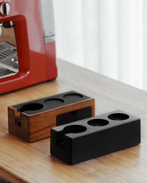 Walnut 4 In 1 Espresso Knock Box And Tamping Station with black and walnut finish on wooden counter near espresso machine.