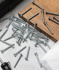 Bulk Pack 8-32 X 1-3/4 Inch Zinc Plated Cabinet Knob And Pull Machine Screws Kit scattered on wood surface