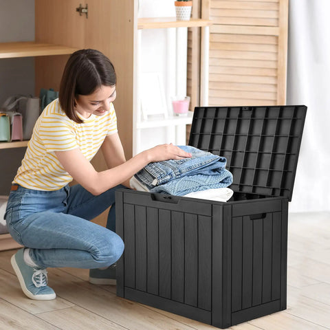 Woman using 30 Gallon Outdoor Storage Deck Box Made From Waterproof Resin With Lockable Lid For Cushions Pool Accessories And Garden Tools