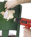 Dual Temperature 1500W Heat Gun Workhorse With 575 To 932 Degrees Fahrenheit Settings in use for paint removal on chair