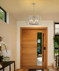 Top Tier Six Light Modern Metal Geometric Chandelier In Sleek Brushed Nickel hanging above a wooden front door in an entryway.