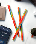 Ropes Candy Twisted Rainbow Punch Flavor Soft And Chewy 9 Oz Pack on a table with smartphone and sunglasses.
