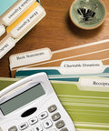 Top Shelf File Folder Labels Featuring Trueblock Coverage And Relentless Permanent Adhesive Engineered For Laser And Inkjet Printers Bulk white sheets arranged with a calculator.