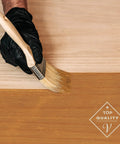 Applying Fast Track Cedarwood Wood Stain for Home Updates with a brush on raw timber surface.