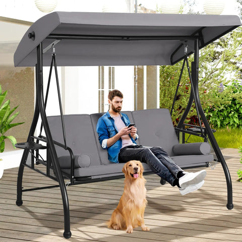3 Seat Outdoor Porch Swing With Adjustable Canopy And Convertible Bed in garden, with man and dog lounging on it