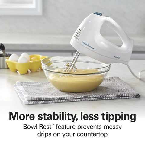 Hamilton Beach 6 Speed Electric Hand Mixer With Quick Burst And Bowl Rest in action mixing batter in a glass bowl.