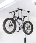 Ceiling Bike Hoist With No Slip Heavy Duty Garage Pulley Lift System For Road MTB Fat Tire And Ebike Storage Space Saving Adjustable Straps For All Bikes Overhead Bicycle Hanger Fits Ceilings Up To 14 Feet showing mountain bike suspended from ceiling.