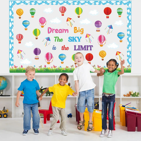 Children in front of Dream Big Bulletin Board Set 66 Pieces With Hot Air Balloons Cloud Borders 3D Honeycombs Kites And Sky Themed Decor