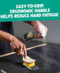Heavy Duty Interior Carpet And Upholstery Detailing Brush With Durable Bristles For A Deep Clean Of Car Mats Seats And Fabric Ergonomic Grip For Comfort And Total Control being used on a car mat with cleaning spray.