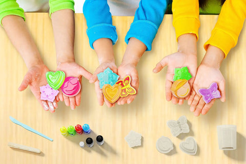 Children showcasing vibrant soaps made with the Soap Making Kit For Kids Create 8 Colorful Soaps With Fragrance And Glitter Using Four Molds A Kid Approved Hands On Science Craft For Boys And Girls Aged 6 To 12 A Fun Educational Gift, surrounded by dyes and molds on a table.