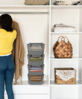 Woman organizing clothes in closet with Stackable Plastic Storage Bins 4 Piece Gray Set For Home And Kitchen Open Front Design