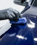 Close-up of GYEON MOHS ceramic coating kit being buffed on blue car hood with blue applicator pad