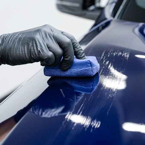 Close-up of GYEON MOHS ceramic coating kit being buffed on blue car hood with blue applicator pad