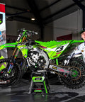 Motocross rider next to green Kawasaki bike highlighting Rear Wheel Bearing Kit for Kawasaki KX125 KX250 KX500 1997 to 2004 OEM Quality Bearings and Seals Direct Fit Heavy Duty Hub Load Ready Durable Cost Effective Replacement for Trail and Track Riders.