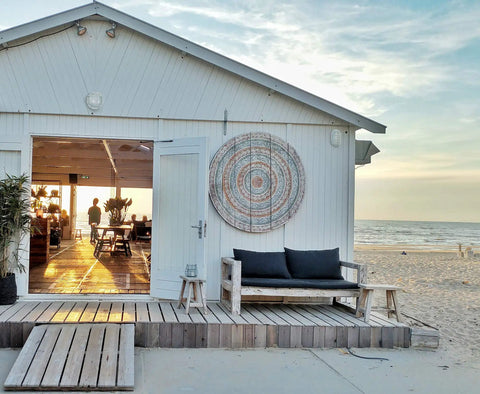 Beachfront cabin with large circular decor, outdoor seating, and sunset view