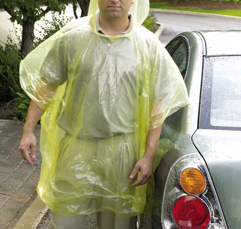 Man wearing yellow rain poncho next to car reflecting light rain