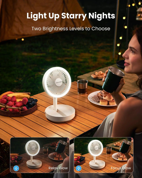 Foldable Desk Fan With LED Night Light 6.8 Inch Wireless Portable Fan at night on a table, person holding a drink outdoors.