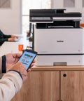 Color Laser All In One Printer With Duplex Printing, Scan And Copy in an office setting used for scanning documents with a smartphone.
