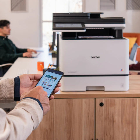 Color Laser All In One Printer With Duplex Printing, Scan And Copy in an office setting used for scanning documents with a smartphone.