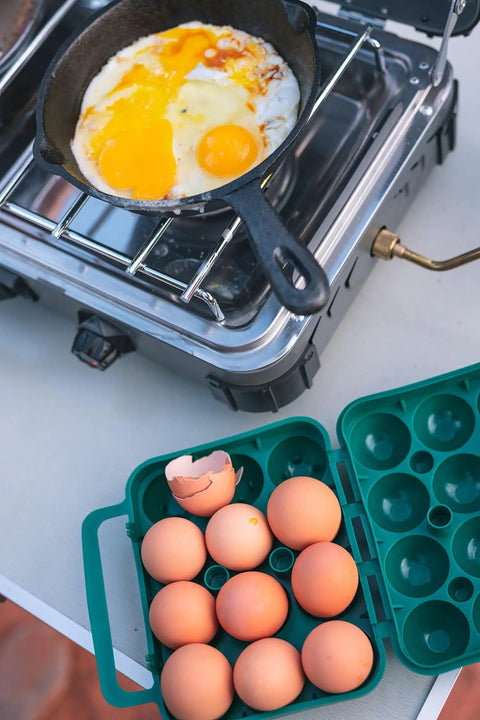 Tough 12-Egg Plastic Carrier With Locking Lid and eggs beside a pan on a camping stove