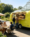 Ready Roll Yellow Food Truck For Pasta And Catering Hustle Packaged With A Full Commercial Kitchen And Private Restroom serving customers in a park.