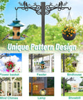 Outdoor decorative metal post with two arms for hanging feeders, baskets, wind chimes, and a lamp in garden setting.