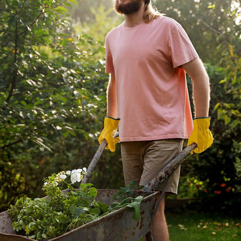 Person wearing Tough Cowhide Leather Work Gloves With Flex Grip For Wood Cutting, Construction, Driving, And Gardening For Men And Women, pushing wheelbarrow.