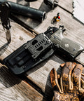 Tough As Nails USA Made Belt Clip Attachment For Concealed Carry Holsters with knife and gloves on rustic wood.