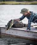 Angler using Ultra Lightweight Fly Fishing Vest With 14 Pockets And Front Zip Storage Olive Green on dock, holding caught fish.