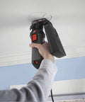 Person using Badass Job Site Ready 6 Amp Roto Spiral Saw Kit with dust attachment to cut drywall on ceiling.