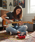 Guitarist using a compact loop pedal with 24 segment circular LED indicator for quick Rec, Overdub, and Play status at home.