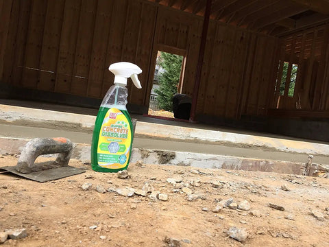 Green Concrete Dissolver Foam Spray 22oz bottle on construction site near trowel and dried concrete, non-corrosive biodegradable formula.