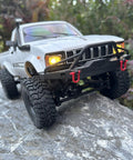 Rugged One Sixteenth Scale RC Rock Crawler Truck 4x4 with Realistic Interior on rocky terrain, showcasing LED lights and front bumper