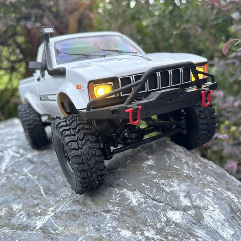 Rugged One Sixteenth Scale RC Rock Crawler Truck 4x4 with Realistic Interior on rocky terrain, showcasing LED lights and front bumper