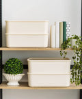 Two off-white 15 Quart Plastic Storage Bins With Lids 4 Pack Stackable Organizer Bins For Kitchen Bathroom And Bedroom on a shelf