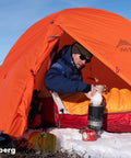 Camper using Windproof Camping Stove System With Radiant Burner And Regulator Fast Boil 1.8 Liter Pot inside orange tent.