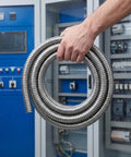 Kickass Stainless Steel Flexible Metal Conduit For Wire Protection 1 Inch X 9.8 Feet being held with a hand in an industrial setting.