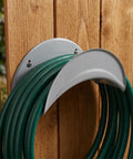 Heavy Duty Wall Mount Hose Hanger 2 Pack Sturdy Iron Metal Rack holding green hoses on wooden wall.