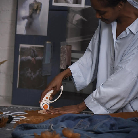 Person using 45mm Rotary Fabric Cutter With Ergonomic Loop Grip for Easy Precise Cuts on fabric in craft room