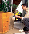 Man using Control Spray Max HVLP Paint and Stain Sprayer With Fully Adjustable Settings For Decks Cabinets Furniture And Woodworking Includes Extra Container In Bright Yellow And Black For A Smooth Finish On Thin Materials on wooden cabinet