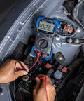 Hands using pro grade automotive digital multimeter with auto range and overload protection in car engine diagnostics