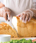 Person wearing Industrial Grade Clear Vinyl Gloves Disposable Powder Free Latex Free Non Sterile Food Safe slicing bread