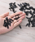 Close-up of black metal picture frame turn-button fasteners and screws in hand (100-piece set)