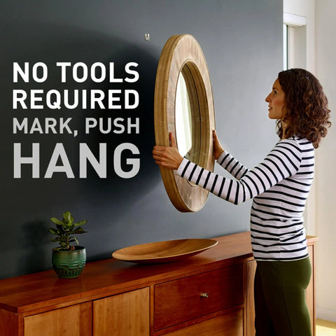 Person hanging round wooden mirror using Claw Drywall Picture Hanger Variety Pack With Spot Markers For Heavy Mirrors And Frames.