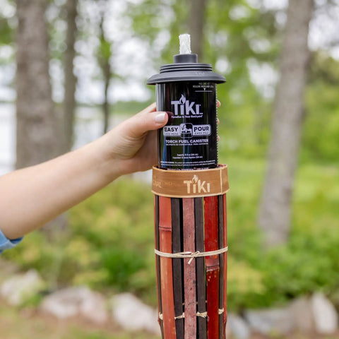 Person holding easy pour canister on 60 Inch Bamboo Torches 4-Pack With Easy Pour 12 Oz Canisters, Long-Lasting Fiberglass Wicks And Snuffers, Outdoor Patio Garden Lawn Decor In Walnut And Pecan Finish