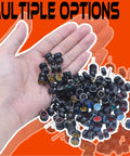 Hand holding 1/64 Scale Diecast Car Wheels And Tires Set Mixed Random Realistic Wheel Rims With Printed Detail For Customizing Cars Variety Pack For 1/64 Models Great For Collectors And Hobbyists on orange background.