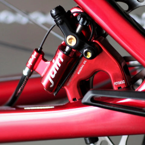Juin F1 Hybrid hydraulic disc brake caliper, red, mounted on bicycle fork