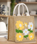 Beginner Punch Needle Kit With Tote Bag showcasing floral embroidered design on burlap material, displayed on a table.
