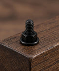 Black Furniture Connector Bolts And Barrel Nuts 40 Piece Kit For Rock Solid Bed Frame And Cupboard Assembly close-up on a bolt mounted in wood.